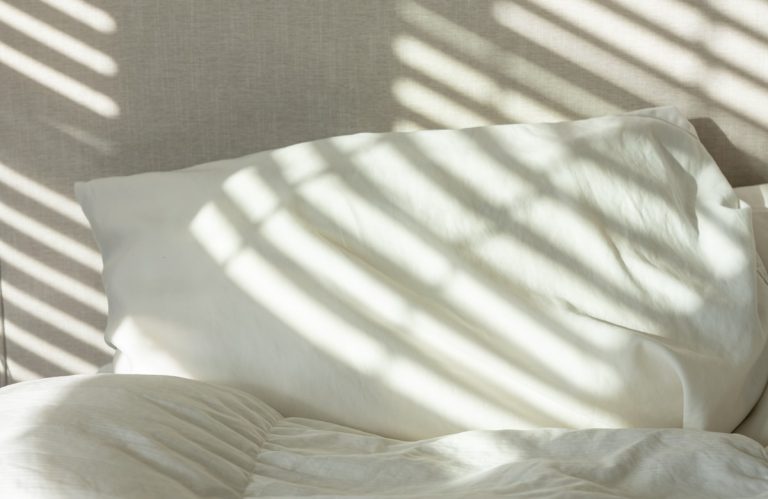 Bedroom with the bed made up in fresh white linen and towels placed ready for the next guest